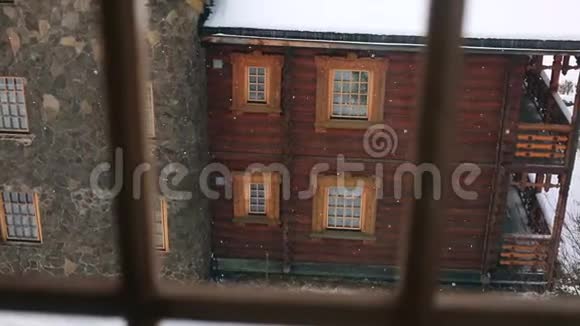 在大雪期间透过窗户观看山村的木屋落在木屋上的雪视频的预览图