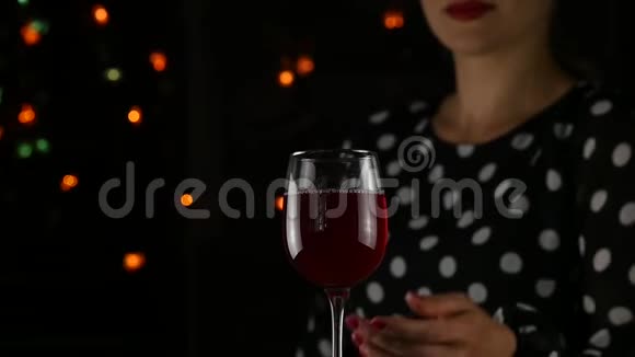 美丽的年轻女子在黑暗中喝红酒带着一杯酒的美女慢动作视频的预览图