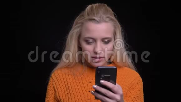 特写照片上年轻漂亮的白种人女性在手机上浏览然后看着镜头微笑视频的预览图