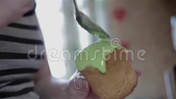 女孩厨师在一个小的复活节蛋糕上涂上一个大勺子釉特写烹饪食物视频的预览图