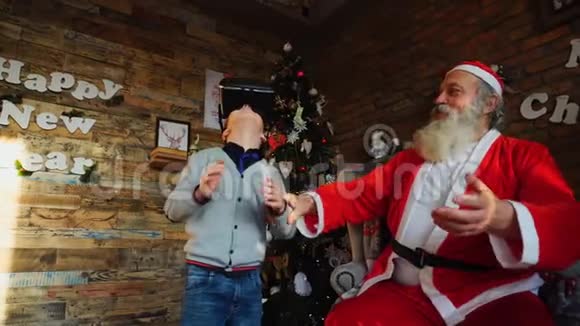 精力充沛的小男孩在虚拟现实眼镜中玩有趣的游戏由圣诞老人装饰视频的预览图