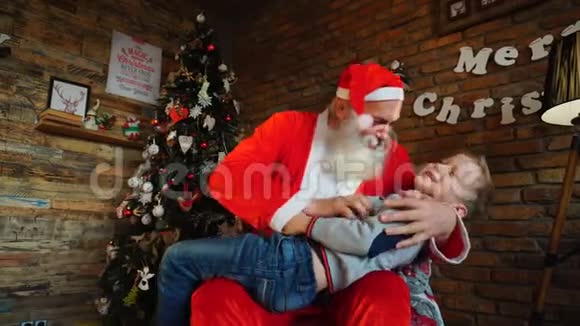 神奇的圣诞老人和小男孩一起在为圣诞节装饰的漂亮房间里玩得开心视频的预览图
