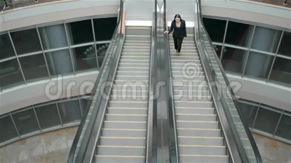 自信的女人正在通过手机上网看电子邮件而站在自动扶梯的购物中心视频的预览图