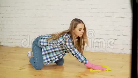 专心擦木地板的女人年轻女孩在防护手套洗涤公寓春季清洁概念视频的预览图