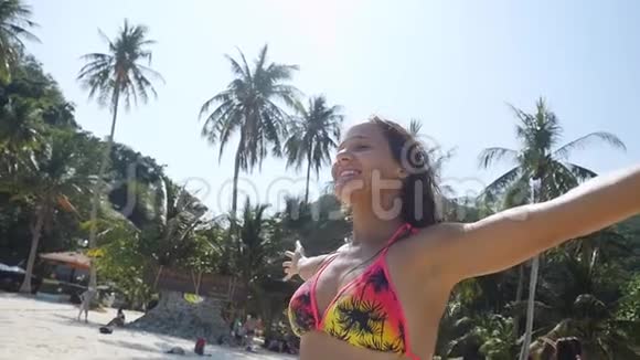 暑假里一个双手伸直的女人在沙滩上玩在阳光下跳舞慢动作地旋转视频的预览图