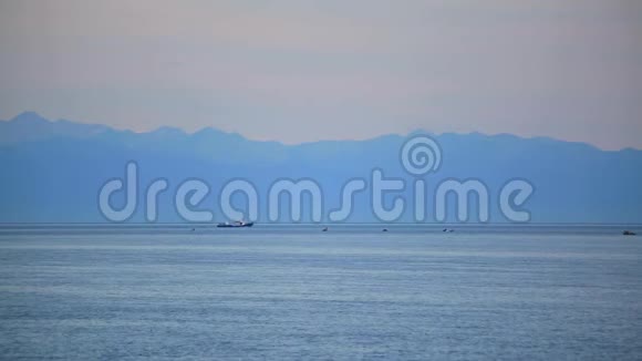 在贝加尔湖岸边的山脉背景上的船视频的预览图