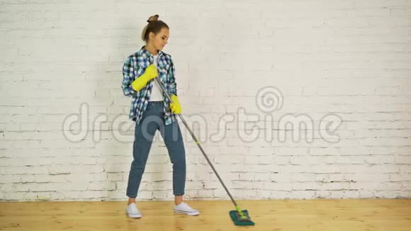 美丽的年轻女子正在跳舞微笑着在家里用拖把清洁地板视频的预览图