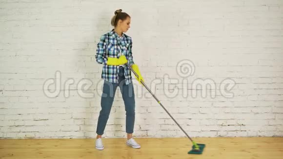 美丽的年轻女子正在跳舞微笑着在家里用拖把清洁地板视频的预览图
