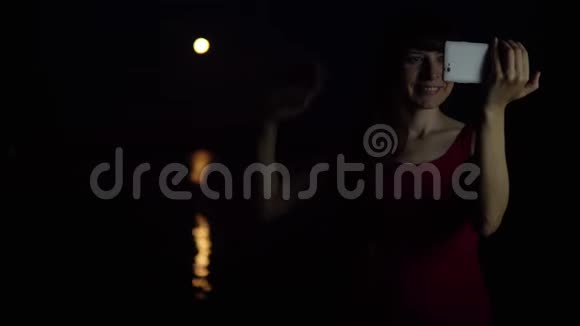 一个年轻的女人用智能手机相机对着红月自拍视频的预览图