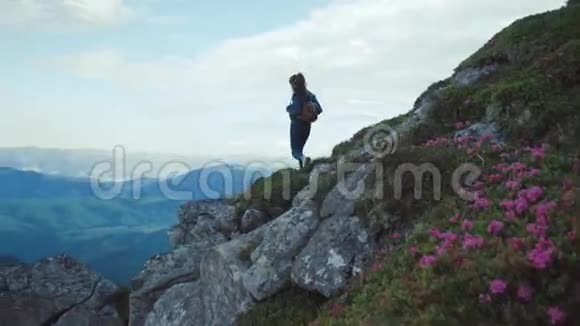 美丽的年轻女子背着背包独自站在高高的山上欣赏着风景美丽的自然华丽的视频的预览图