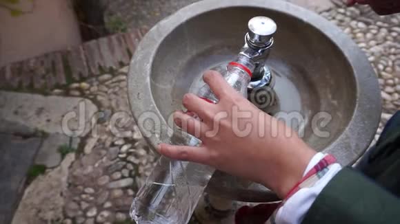 从格拉纳达的公共典型喷泉中用水填充回收瓶的人手视频的预览图