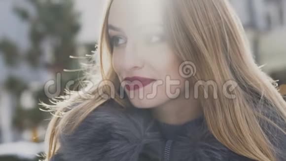 迷人的女孩在冬天的街道上对着镜头微笑慢慢地视频的预览图