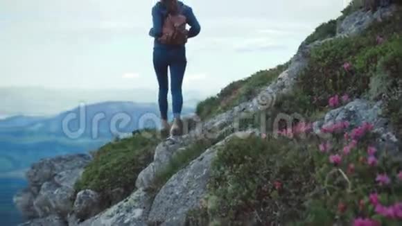 年轻漂亮的女士背着背包穿着运动服装在山上游荡站在危险的高度欣赏风景视频的预览图
