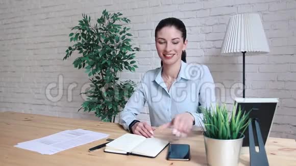 一个女人在办公室的一张桌子上打电话视频的预览图