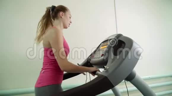 一个迷人的女孩正在健身房的跑步机上工作视频的预览图