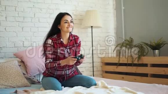 女孩在家里的床上玩控制台生活方式和技术的概念视频的预览图