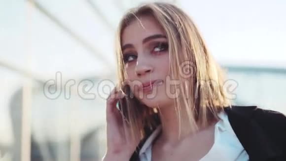 旋转的视角一个迷人的年轻金发女人与自然化妆在她的电话成功的事业现代视频的预览图