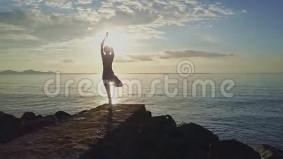 女人剪影瑜伽对抗海洋之上的太阳视频的预览图