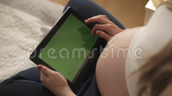 孕妇使用带有绿色屏幕的数字平板电脑视频的预览图