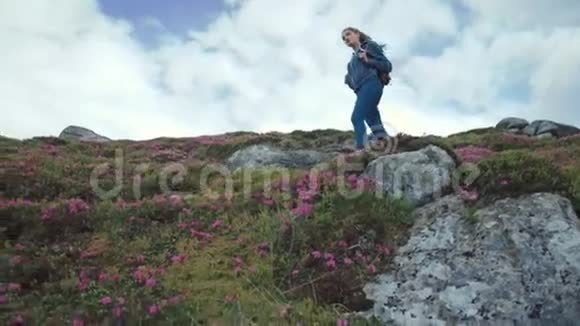 小角度拍摄一位年轻的旅游妇女背着背包走下花山欣赏风景视频的预览图