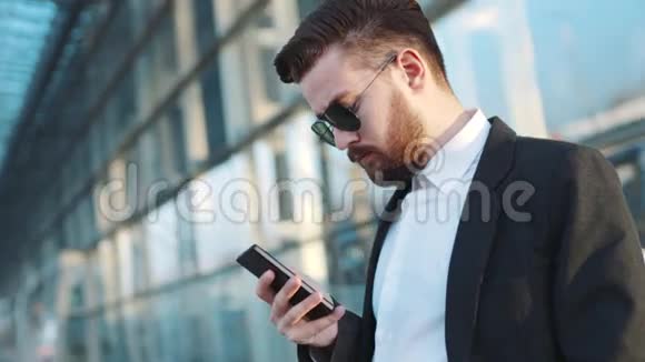 旋转视角的英俊胡子男子站在机场航站楼和使用电话环顾四周等待视频的预览图