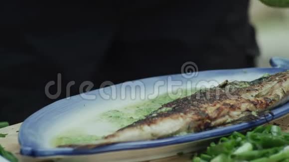 厨师把煎湖奥赫里德棕色鳟鱼A从平底锅到一个盘子与绿色酱汁视频的预览图