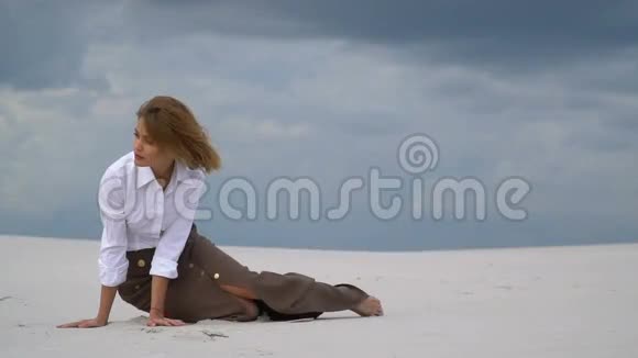 神秘的金发女郎坐在沙漠里视频的预览图