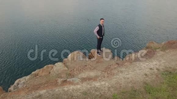 人站在湖边的悬崖边视频的预览图