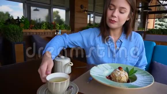 欧洲女孩在餐馆喝茶然后慢慢地吃蛋糕视频的预览图