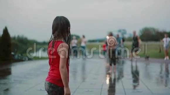 湿漉漉的小女孩站着玩水站在喷水池上快乐的孩子在炎热的夏天玩得开心视频的预览图
