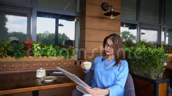 迷人的女人在餐馆看报纸慢吞吞地喝茶视频的预览图