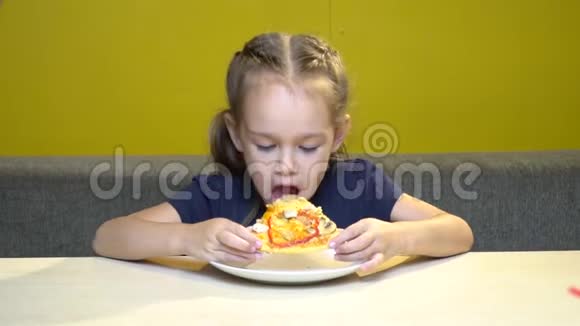 小女孩的肖像在一家有黄色墙壁的咖啡馆里吃披萨视频的预览图