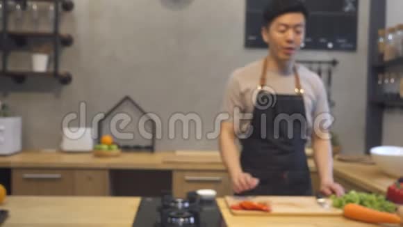 年轻的亚洲男人在厨房用相机录制视频微笑亚洲男人致力于食品博客概念视频的预览图