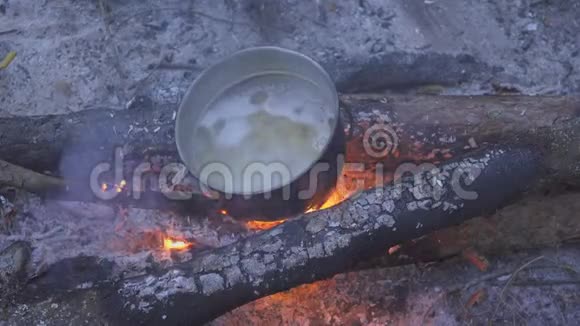 在晚林的篝火上用大锅煮意大利面厨师用勺子搅动食物特写视频的预览图