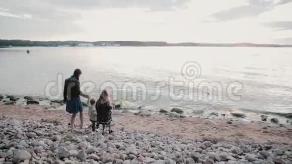 一家三口人在海滩上散步母亲女儿和儿子去喝水牵着手视频的预览图