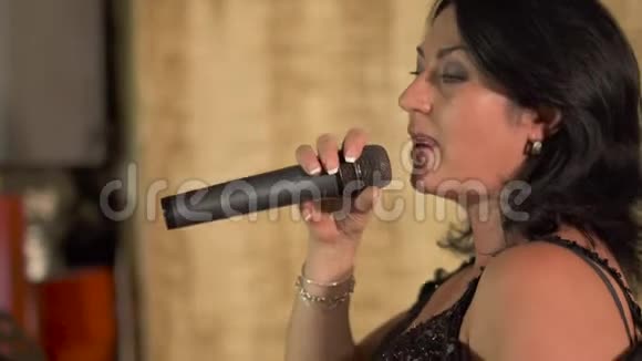 女歌手在餐厅的舞台上用麦克风演唱歌曲视频的预览图