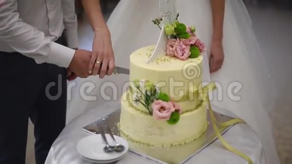 特写新娘和新郎大刀切结婚蛋糕视频的预览图