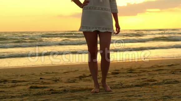 站在海滩上的女人光着脚在夕阳下海滨海洋健康的生活方式观念视频的预览图