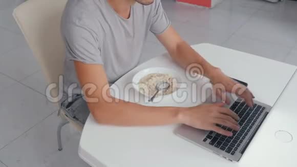厨房里忙着做多任务的商人用笔记本电脑工作吃饭计时视频的预览图