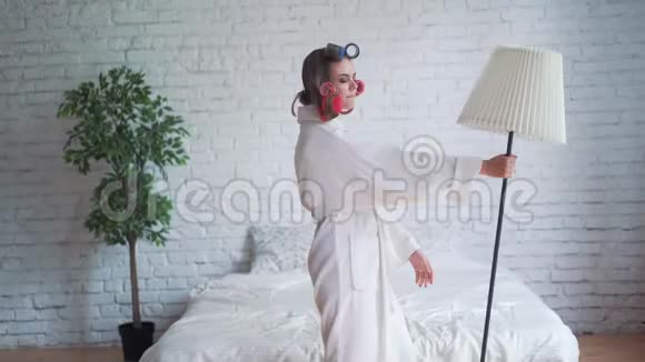 快乐的年轻金发女性她的长发在睡衣跳跃和跳舞在床上早上和微笑妇女视频的预览图