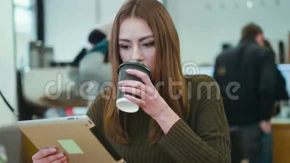 近距离观看一位穿着休闲服的漂亮年轻女士坐在咖啡馆A并使用平板电脑上网视频的预览图
