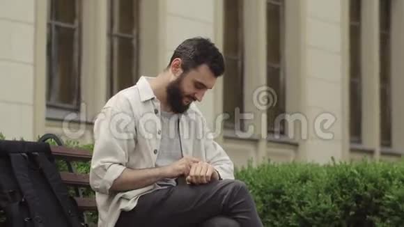 男人用他的智能手表坐在长凳上工作视频的预览图