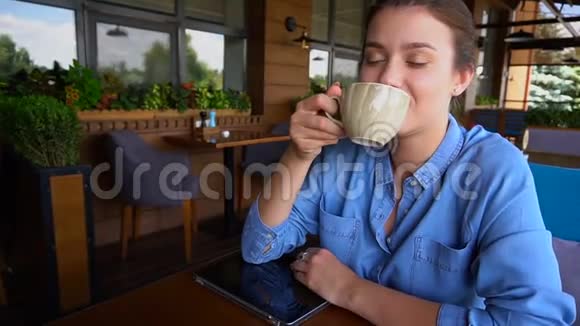 格拉德登的女人喝茶坐在餐馆里慢吞吞地吃着药片视频的预览图