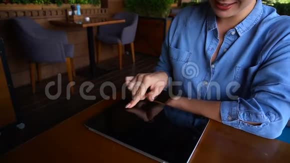 在咖啡馆里女性手指缓慢地触摸平板电脑屏幕视频的预览图