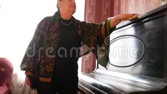 家里的老妇人擦着钢琴上的灰尘视频的预览图