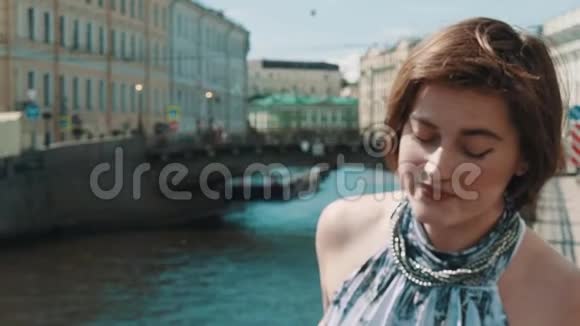 穿着斑点裙子的悲伤年轻女子在老市中心的河边唱歌视频的预览图