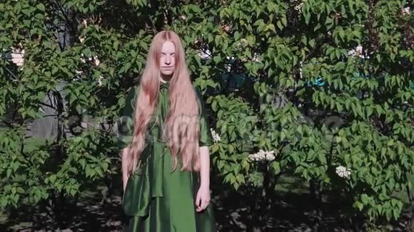 长发红发美女在公园灌木旁微笑视频的预览图
