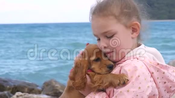 小女孩和她可爱的小狗坐在岩石上视频的预览图