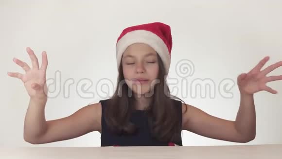 美丽的快乐女孩少年戴着圣诞老人的帽子在白色背景的股票视频中有感情地笑视频的预览图