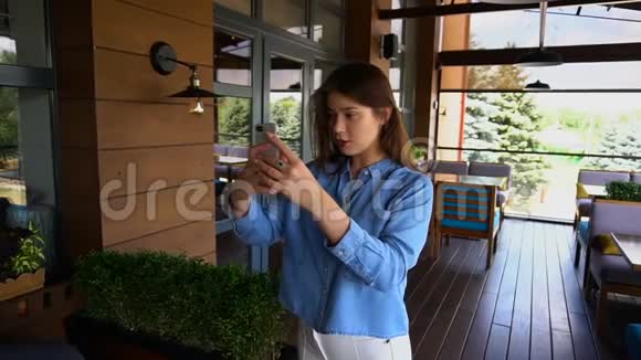 美丽的女士通过智能手机在咖啡馆慢动作自拍视频的预览图